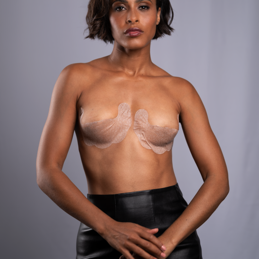 Model standing with hands crossed in front, wearing the adhesive bra. It shows lift and shape. Bra is beige in color.