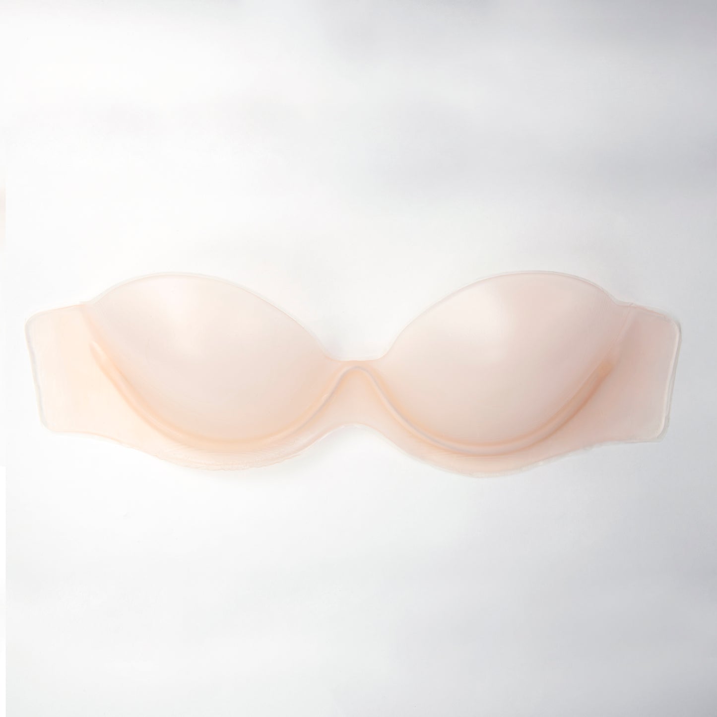 Product image of the body sculpting backless strapless bra. It is mildly transparent and has a fitted shape. The color is transparent nude.