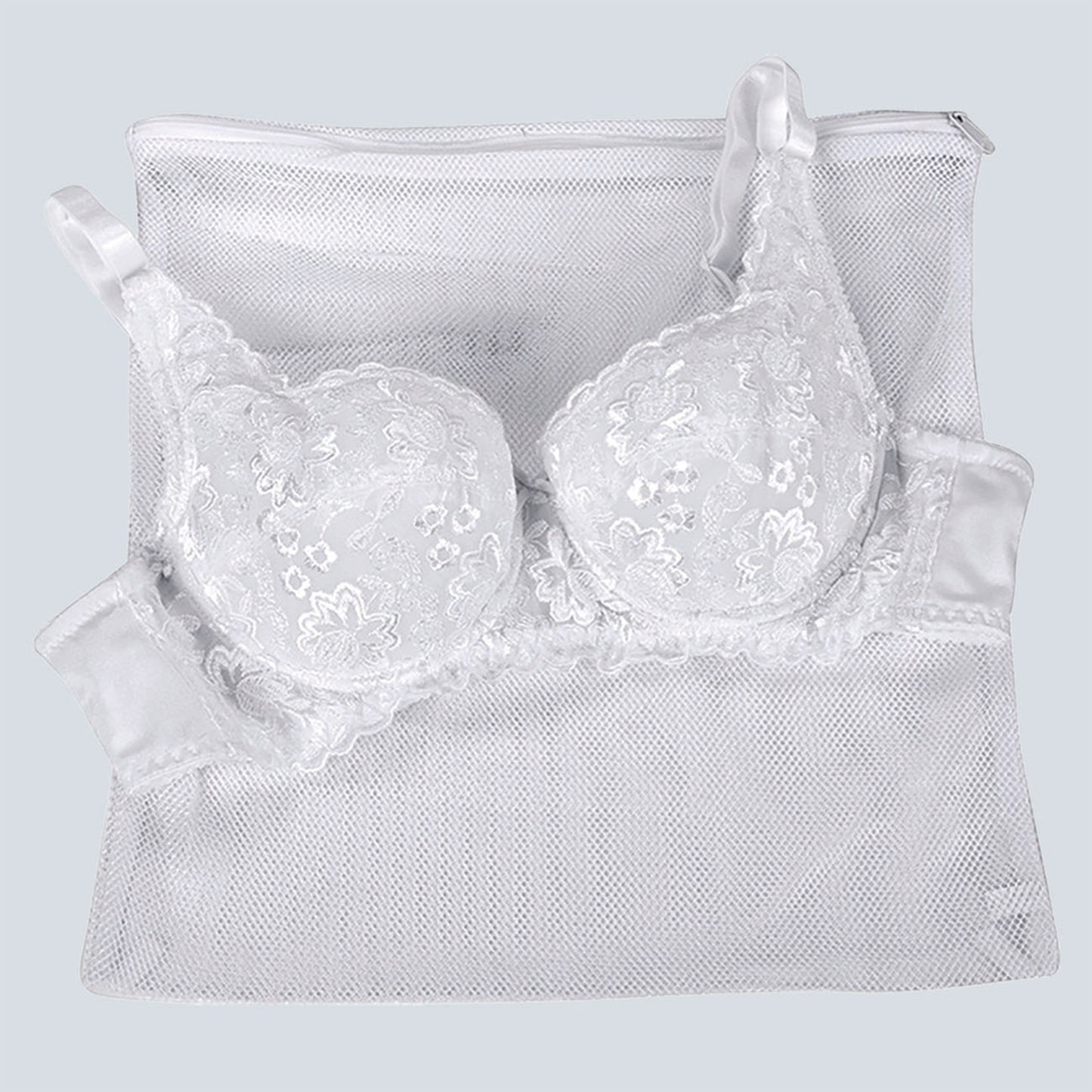 Close up image of the lingerie laundry bag. A lace bra is laid over the top to demonstrate the size. The bag is mesh